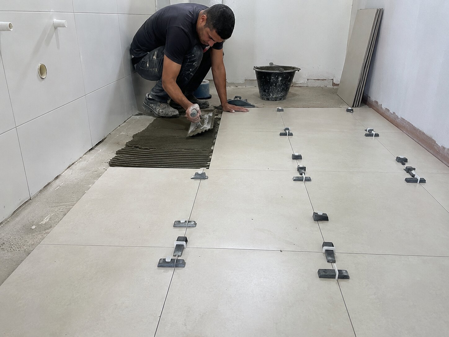 Profissional assentando piso em obra